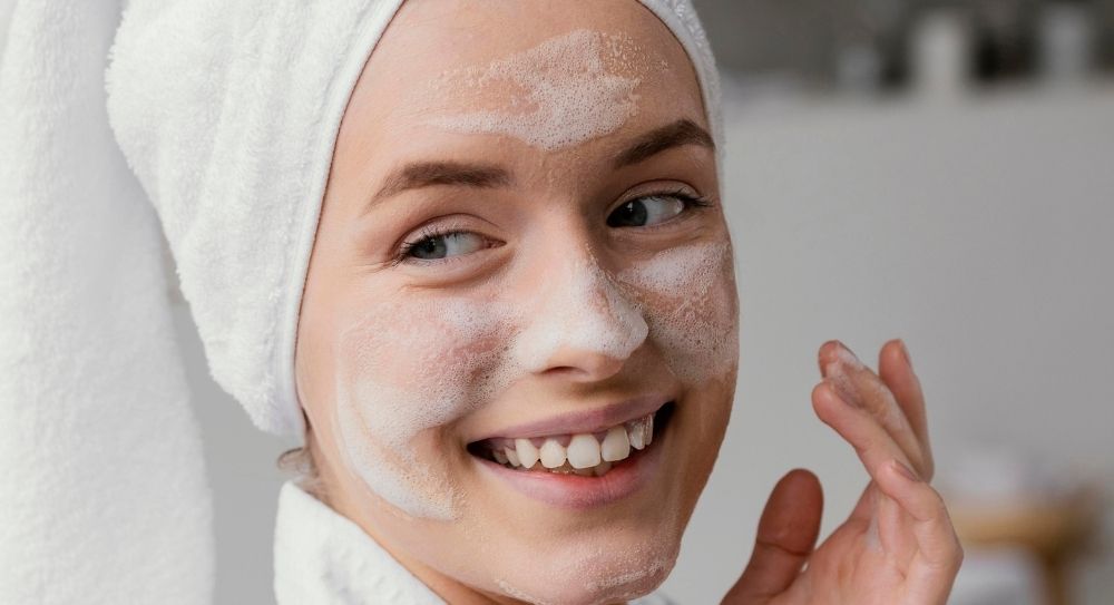 Mlada žena pere lice penušavim sredstvom za čišćenje kao deo pripreme kože pre faceliftinga - Plastične operacije u Turskoj