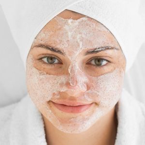 Žena sa peškirom na glavi i blagim pilingom na licu, simbol pripreme kože pre estetske operacije - Plastične operacije u Turskoj